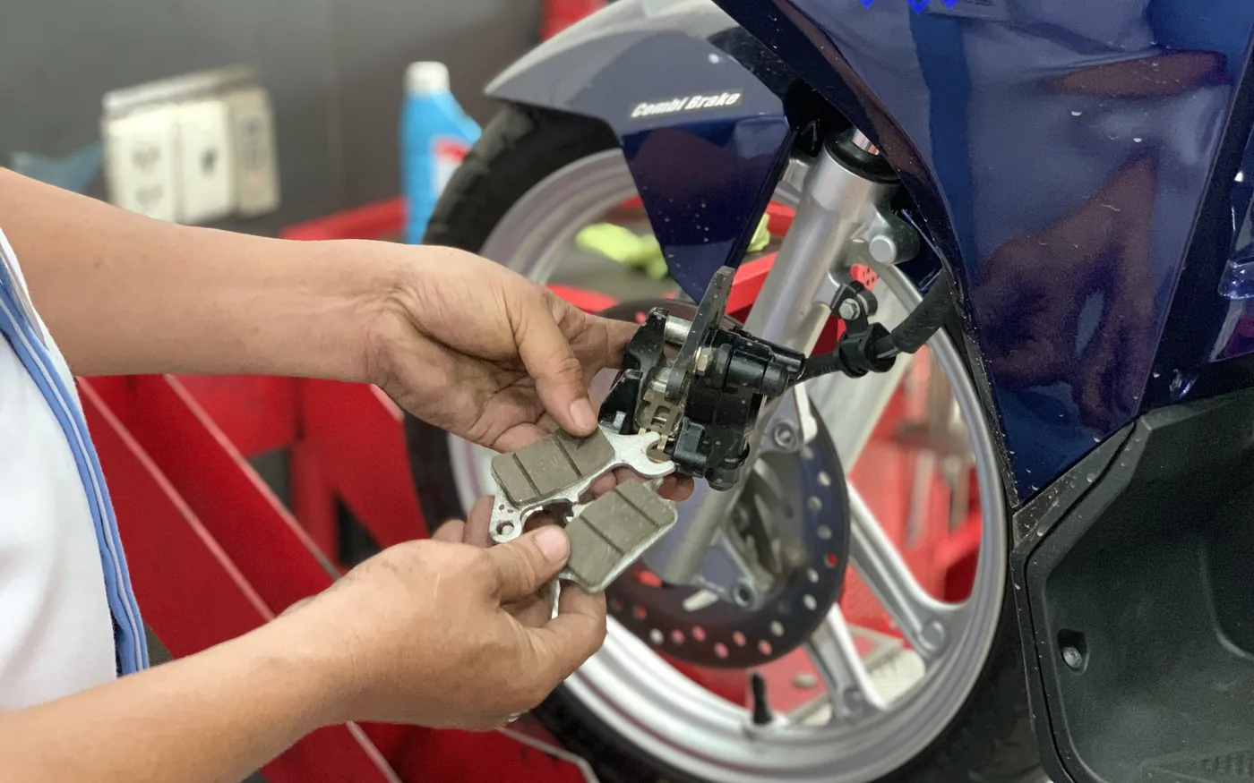 Kỹ thuật viên kiểm tra má phanh và cụm phanh trước của xe