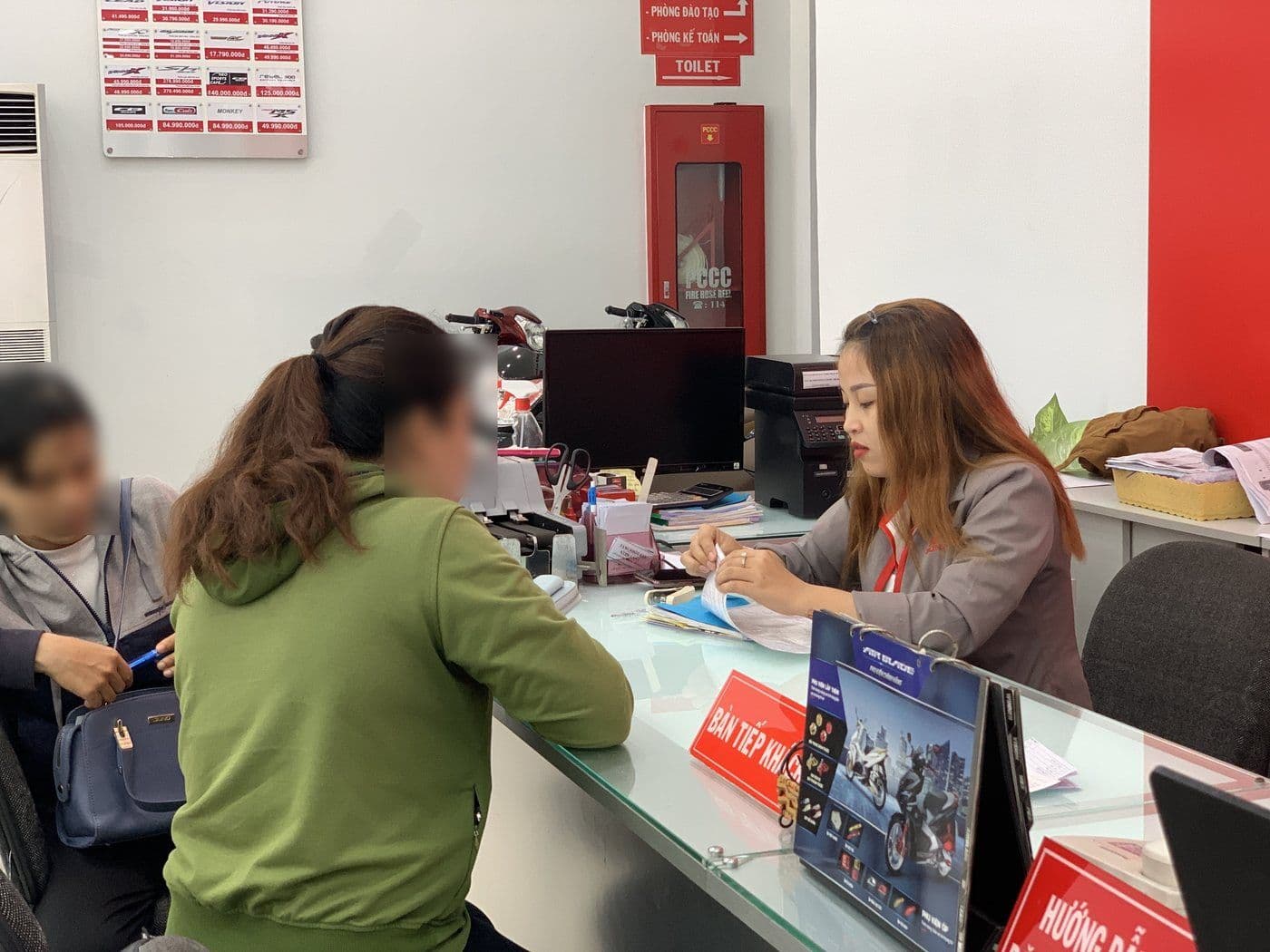 Nhân viên HEAD Khánh An hỗ trợ khách làm hồ sơ mua xe trả góp tại quầy